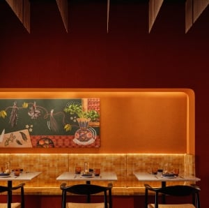 Two seater dining tables with booth seating along a backlit orange accent wall, and black rattan chairs positioned across a marble table.