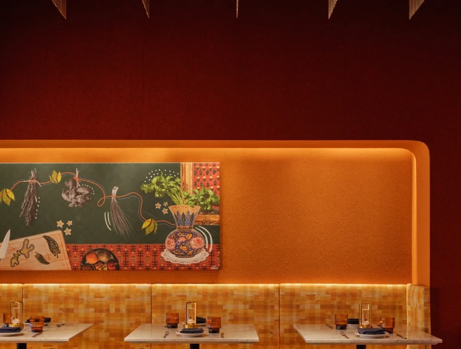 Two seater dining tables with booth seating along a backlit orange accent wall, and black rattan chairs positioned across a marble table.