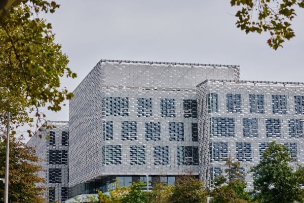 A wide view of the Science and Engineering Complex (SEAS) at Harvard, a large, modern building with a distinctive, patterned exterior facade of metallic panels, framed by trees with fall colors.