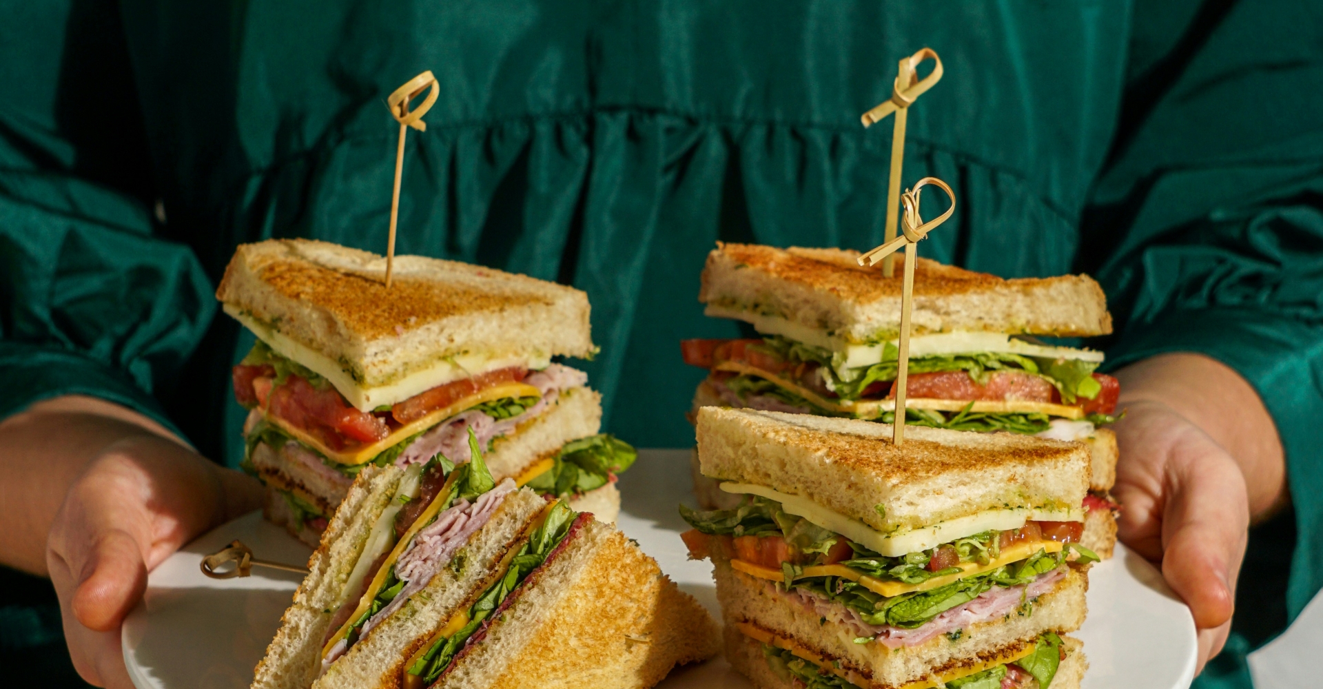 A woman holding a plate full of sandwiches
