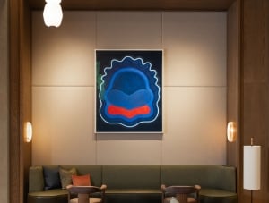 Atlas hotel lobby with curved tan armchairs, a green banquette, wood accents, and a bold abstract painting above the seating area.