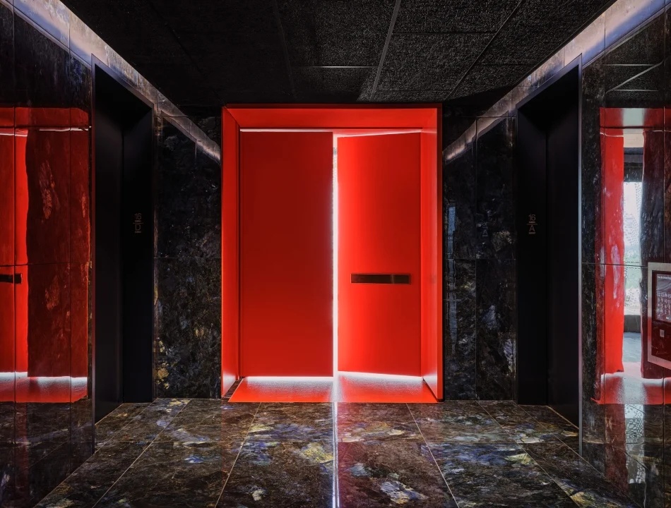 Red illuminated doorway at end of a dark marble hallway with reflective walls